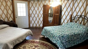 A cozy bedroom with two beds, a wooden wardrobe, a mirror, and a patterned rug.