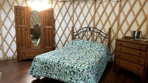 A bedroom with a bed, wooden dresser, and wardrobe.