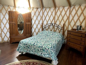 A bedroom with a bed, wooden dresser, and wardrobe.