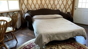 A room with a bed, a chair, a table, and a door.