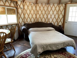 Ein Zimmer mit Bett, Stuhl, Tisch und Tür.