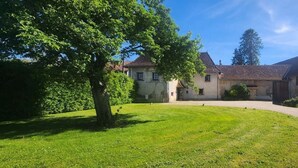 A traditional stone building with a gravel driveway and a well-maintained lawn. - La Tramolière, accommodation in a green setting (Le Passage)