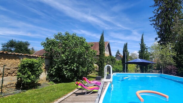 A swimming pool with a wooden deck, lounge chairs, and a sun umbrella. - La Tramolière, accommodation in a green setting (Le Passage)