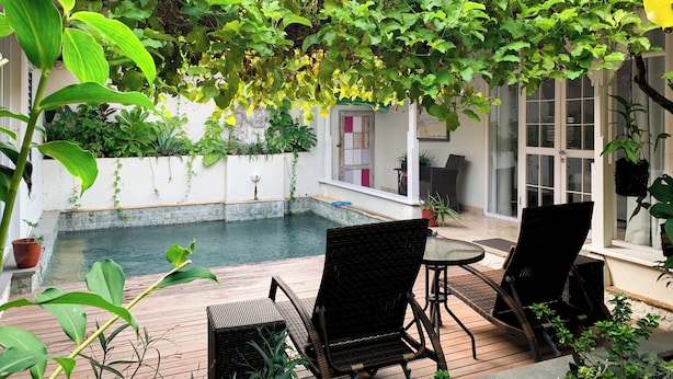 A covered patio with a pool, wicker furniture, and lush greenery. - Tropical Oasis 2 BR Villa Near Beach (Seminyak)