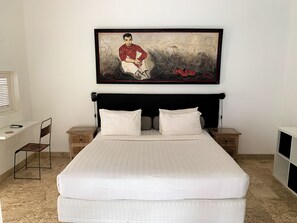 Ein ordentlich eingerichtetes Schlafzimmer mit einem großen Bett, zwei Nachttischen, einem Schreibtisch und einem Stuhl.