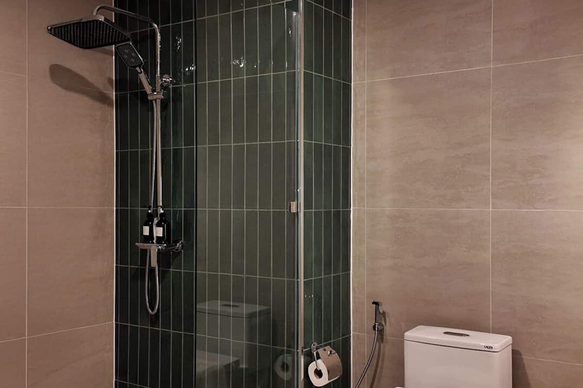 Ein modernes Badezimmer mit einer gläsernen Duschkabine, Toilette und Handtuchhalter.