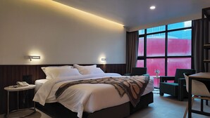 Een moderne hotelkamer met een groot bed, nachtkastjes, een bureau en een stoel.