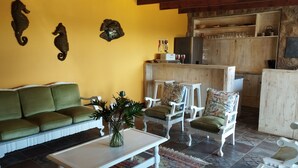 A living room with a green sofa, white armchairs, a coffee table, and decorative wall art. - Billy Bay Cottage (Margate)