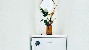 A white refrigerator with a sticker, a vase with flowers, and a mirror on top. - Cozy and Affordable Palace Studio (Vienna)