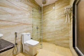 Een badkamer met toilet, douche en een douchecabine met glazen wanden.