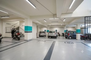 A parking garage with multiple levels, marked parking spots, and a staircase leading to an upper level. - Hotel Sky View at Delhi IGI Airport (New Delhi)