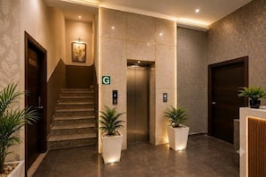 A hotel lobby with a staircase, an elevator, and a reception desk. - Hotel Sky View at Delhi IGI Airport (New Delhi)