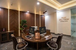 Ein Konferenzraum mit rundem Tisch, vier Stühlen, zwei Laptops, einer Pflanze und einem Schild mit der Aufschrift 'Hotel Sky View Business Center'.