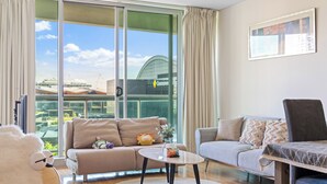 Un salon moderne avec un canapé, une table basse et une vue sur un immeuble à la façade en verre.