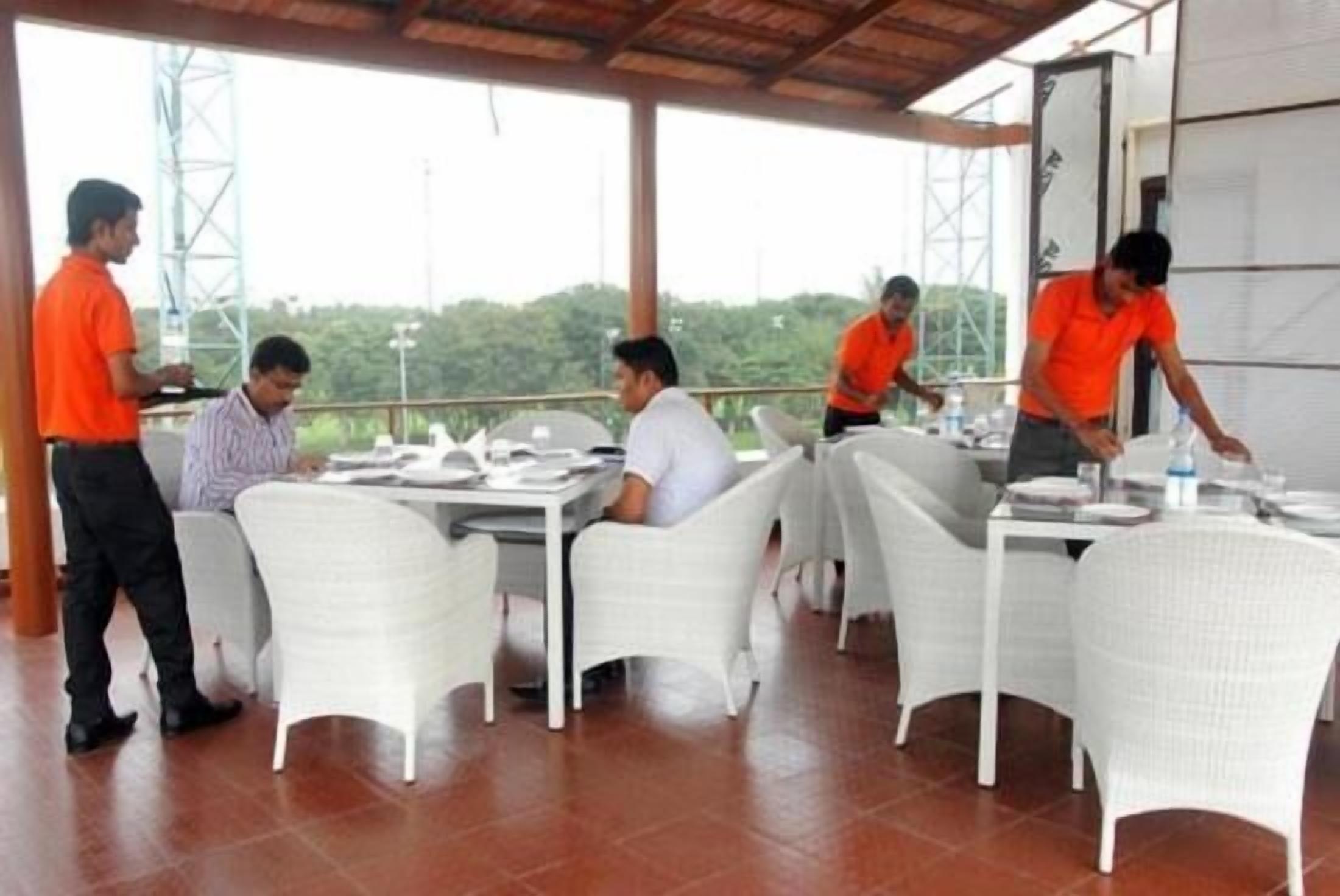 A restaurant with white chairs and tables, a covered outdoor area with a metal structure in the background.