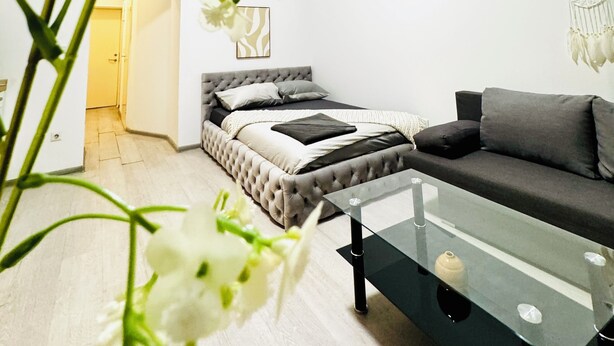 Un dormitorio moderno con cama, sofá y una mesa de centro de vidrio.