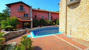 A two-story building with a swimming pool, stone walls, and a red-tiled roof. - Holiday home with air conditioning and terrace (Lignano Sabbiadoro)