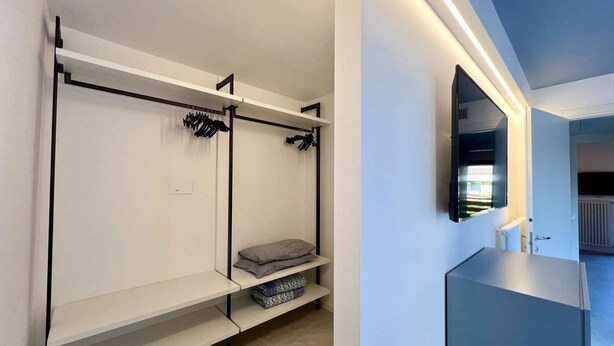 A modern, minimalist room with a bunk bed, a small bench, and a mirror on the wall. - Holiday home with air conditioning and terrace (Lignano Sabbiadoro)