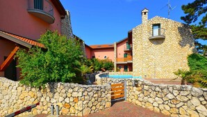 A stone building with a balcony, a pool, and a stone wall. - Holiday home with air conditioning and terrace (Lignano Sabbiadoro)