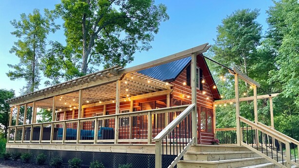 Eine Holzhütte mit überdachter Veranda, einer Treppe und Lichterketten.