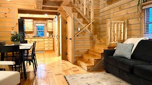 Ein rustikales Holzblockhaus mit Essbereich, Küche, Treppe und Wohnzimmer.