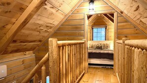 Ein Schlafzimmer im Holz-Giebelgeschoss mit Bett und Fenster.