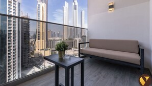 Un balcon avec un canapé et une table, une plante en pot et une vue sur la ville.