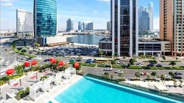 Un quartier urbain moderne, avec de grands immeubles, une vaste piscine et un parking.