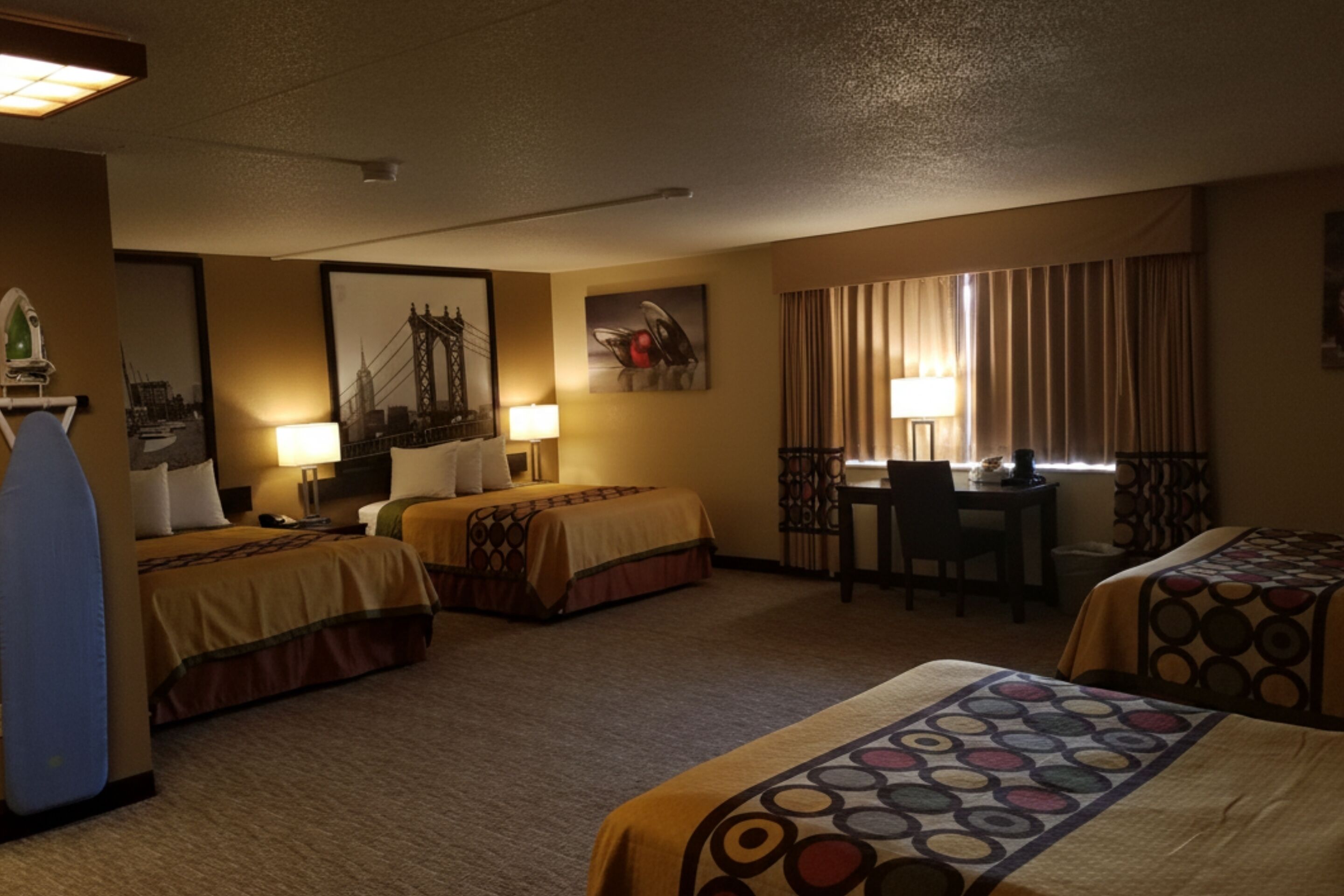 A hotel room with two beds, a desk, a chair, and a window with curtains.