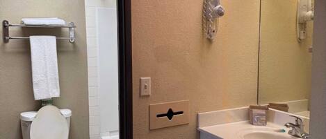 A bathroom with a toilet, sink, and shower.