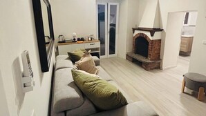 A modern living room with a grey sofa, a fireplace, and a dining area. - Romantic retreat with a private panoramic terrace near the Saturnia Hot Springs (Manciano)