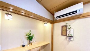 Ein Zimmer mit einem Holztisch, einer kleinen Pflanze, einer Klimaanlage und einem an der Wand befestigten Lautsprecher.