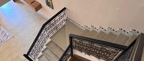 A multi-level interior with a staircase, a small seating area, and decorative wall art.