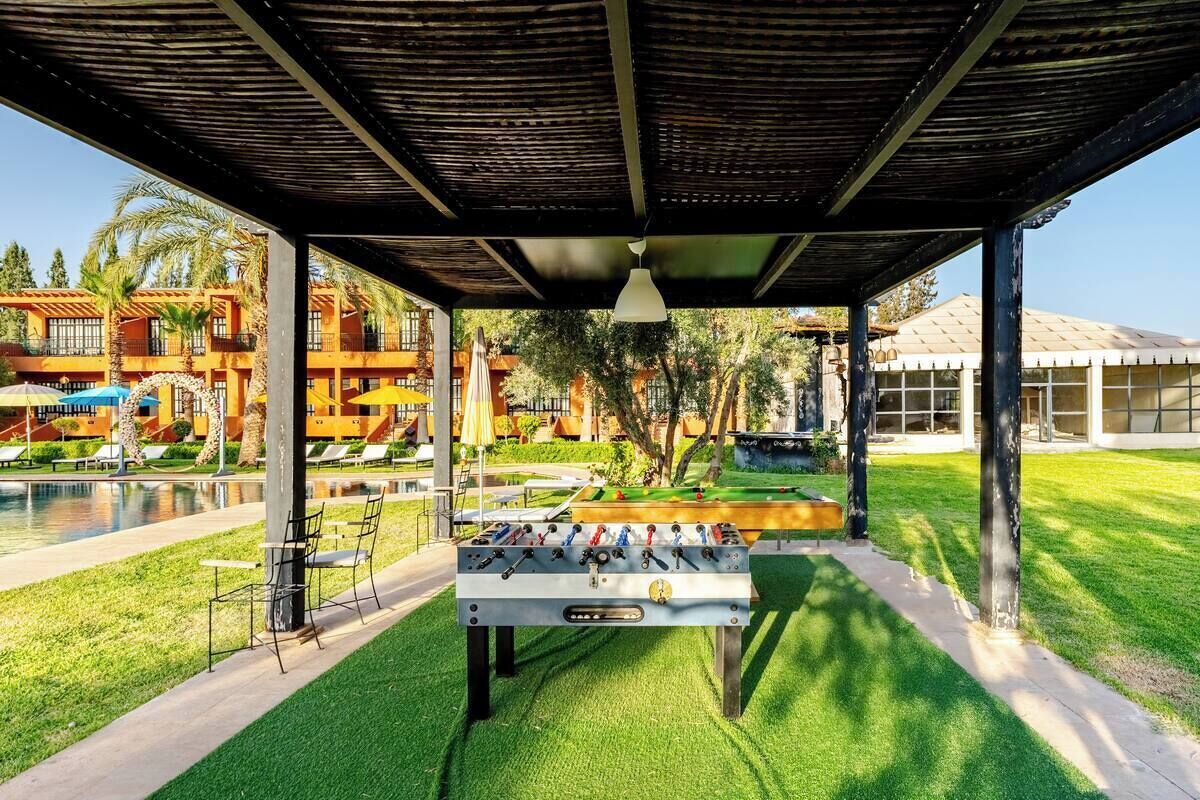 A poolside area with a foosball table, lounge chairs, and a covered seating area.