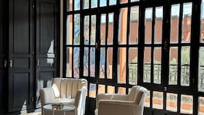 A hotel room with a large window, a bed, a chair, and a small table. - MVIEW Villas (Marrakech)