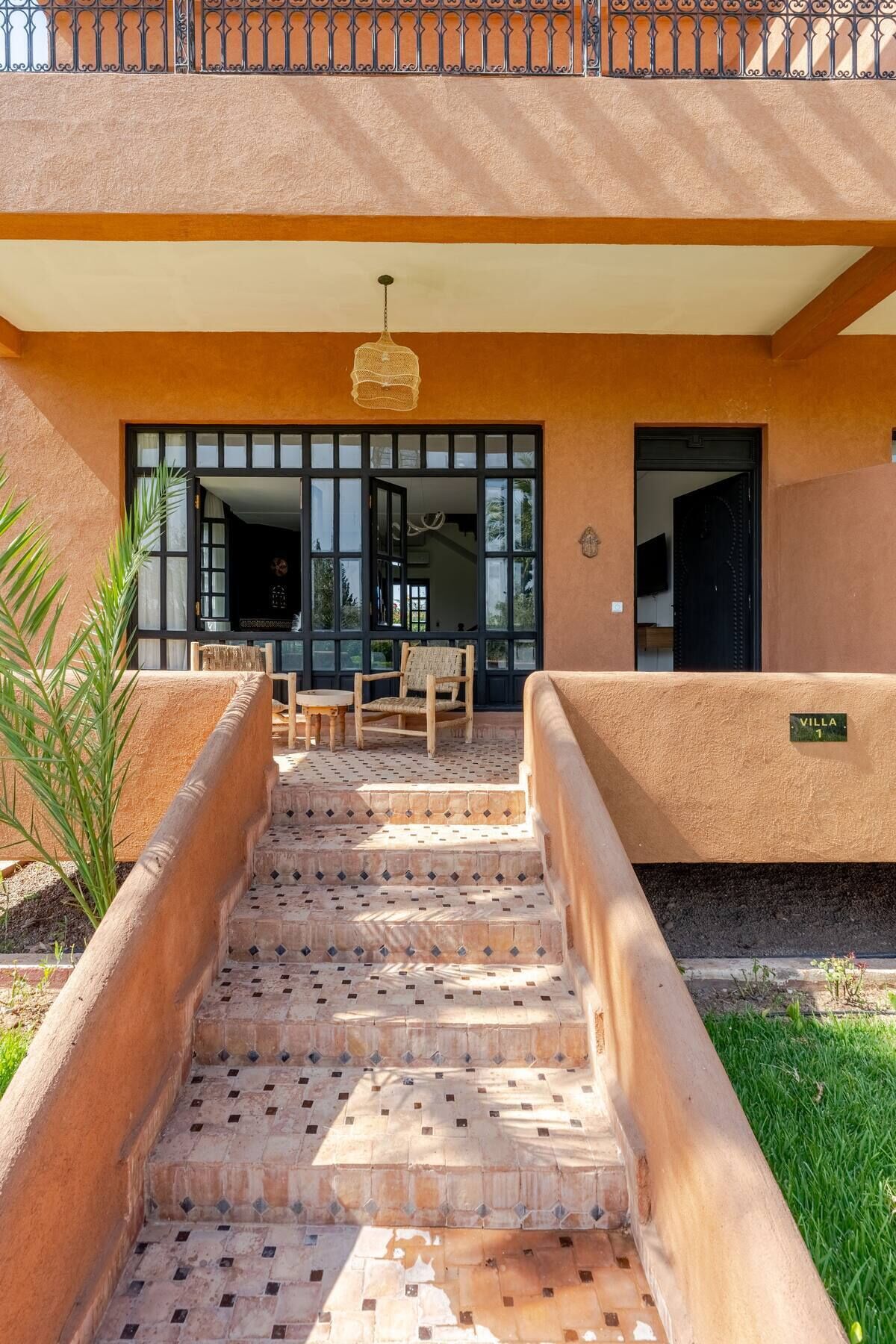 Una entrada de hotel con una escalera de baldosas que conduce a un área de estar cubierta.