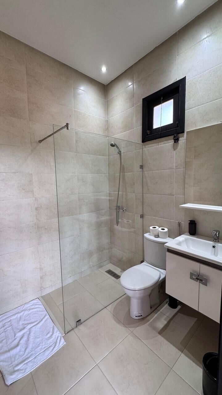 A modern bathroom with a glass-enclosed shower, a toilet, and a sink.