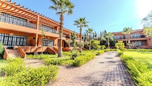 A modern building with a brick facade, multiple balconies, and a paved walkway surrounded by greenery. - MVIEW Villas (Marrakech)