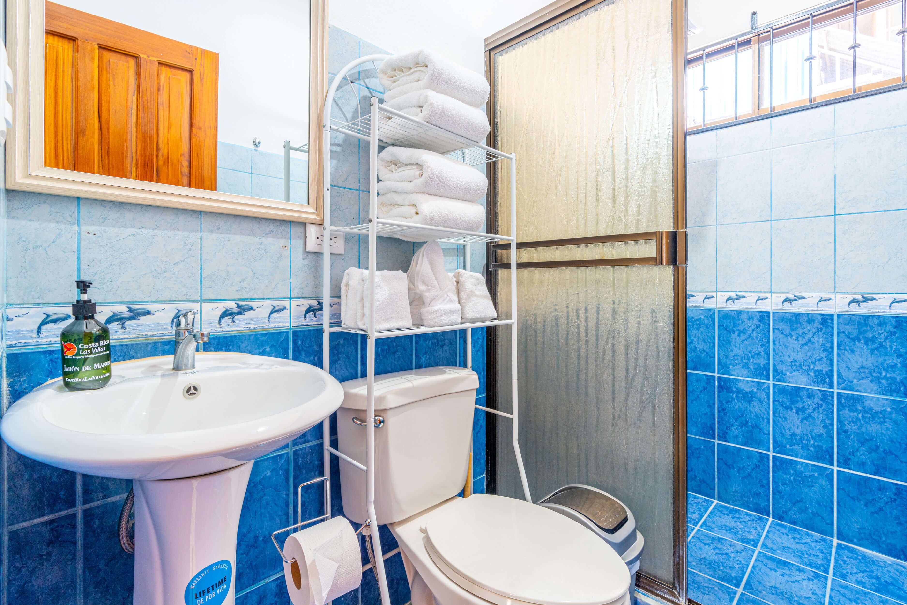 A bathroom with a sink, toilet, and a shelf with towels.