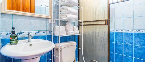 A bathroom with a sink, toilet, and a shelf with towels.