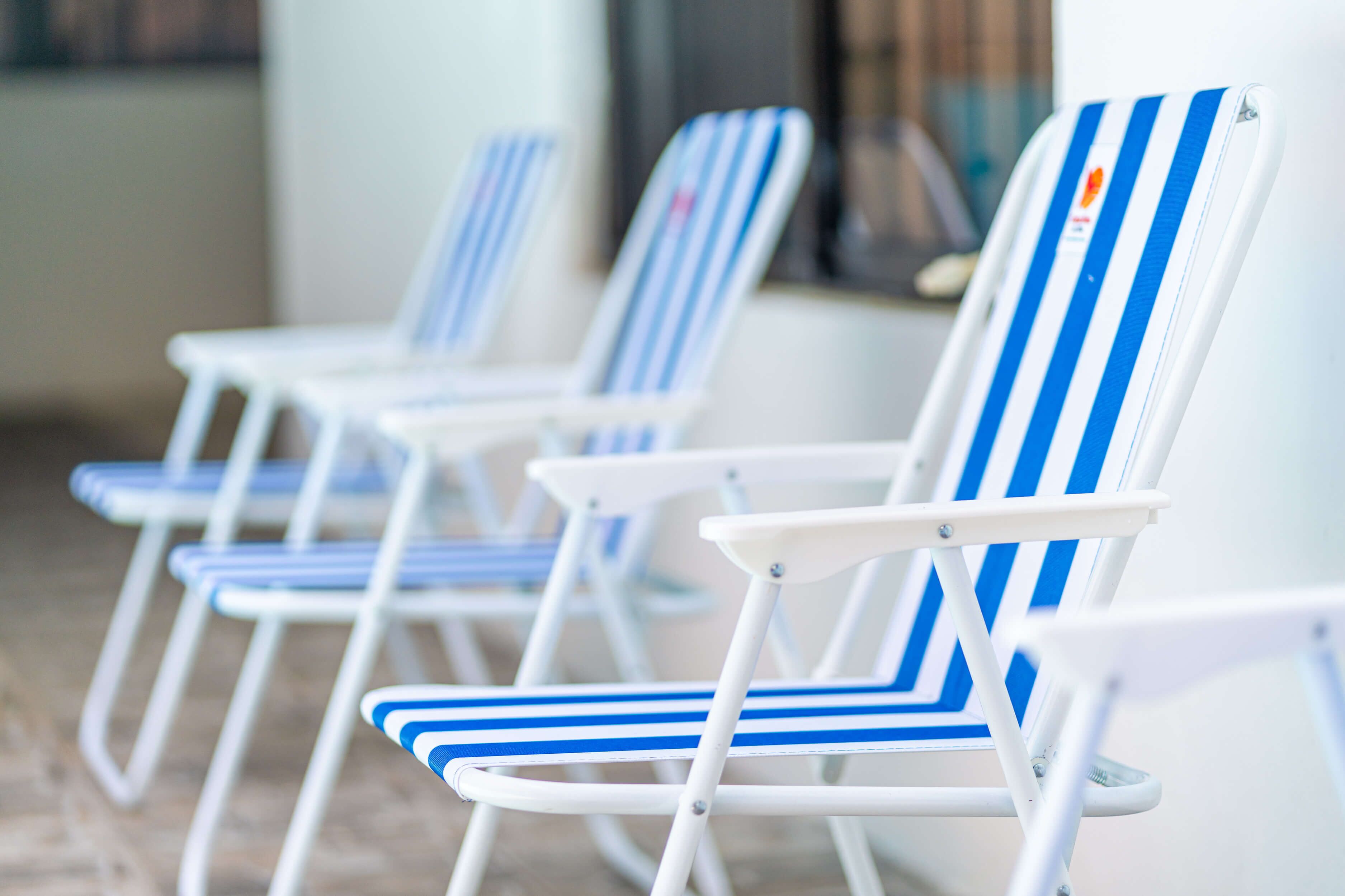 A row of white lounge chairs with blue stripes, arranged in a row.