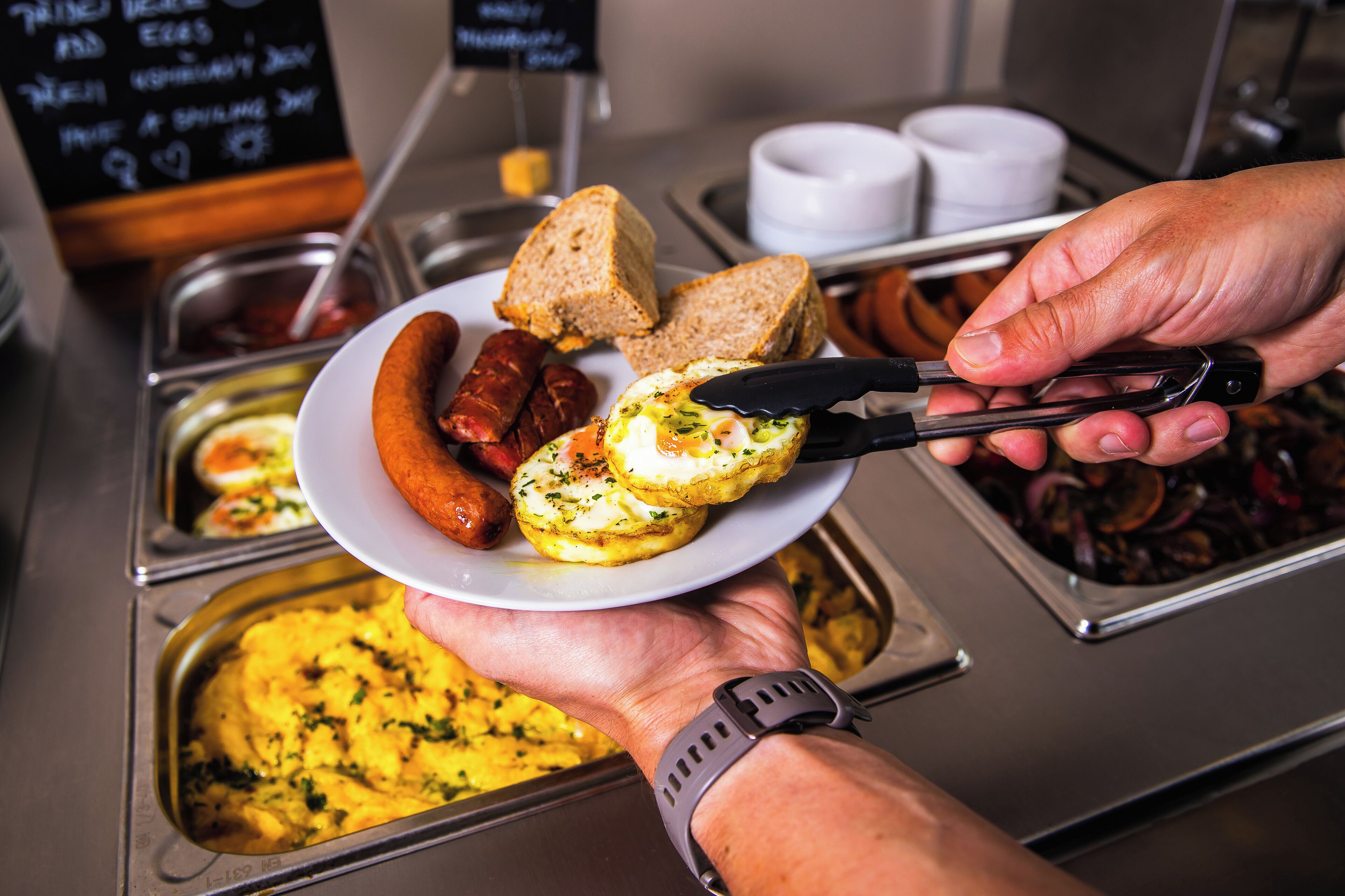 A buffet with various food items including sausages, eggs, and toast.