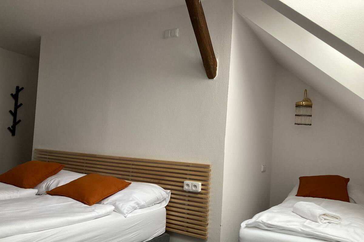Une chambre d’hôtel avec deux lits, une tête de lit en bois, un luminaire fixé au mur et une prise de courant.