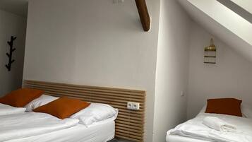 A hotel room with two beds, a wooden headboard, a wall-mounted light fixture, and a power outlet.