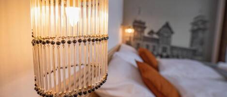 Un candelabro con múltiples detalles colgantes y una cama con almohadas y una manta.