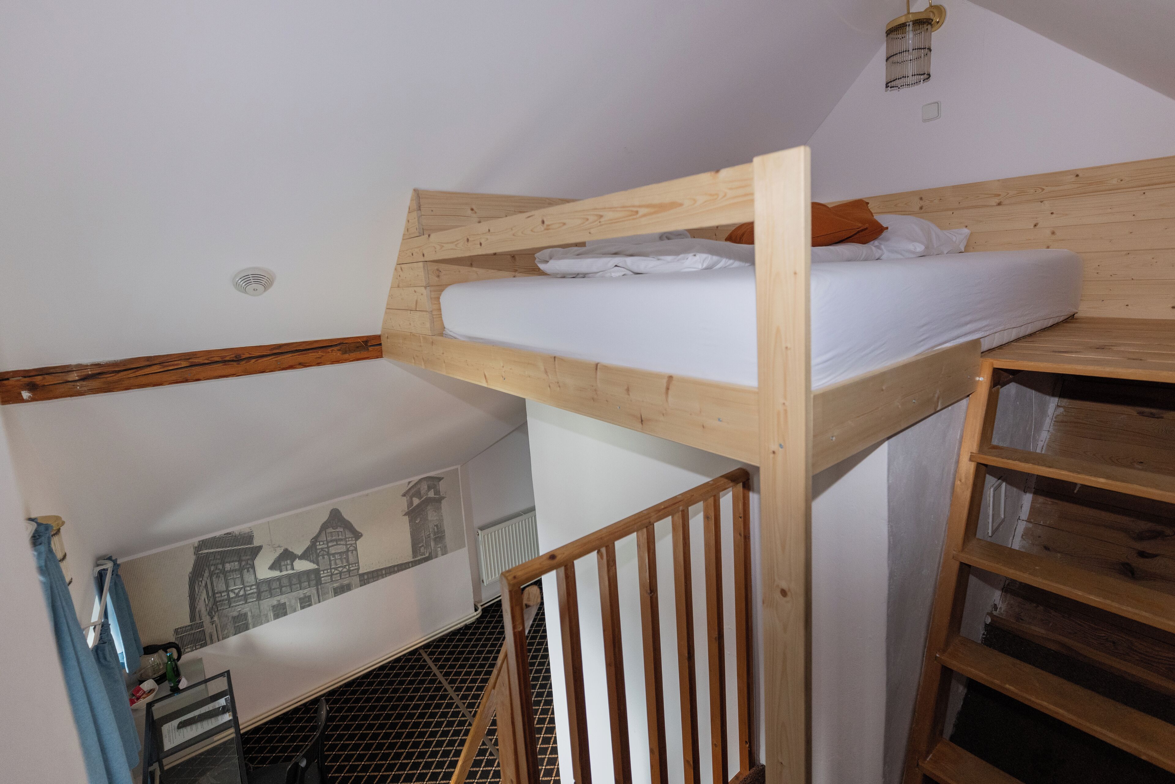A bunk bed with white bedding, a wooden headboard, and a ladder.