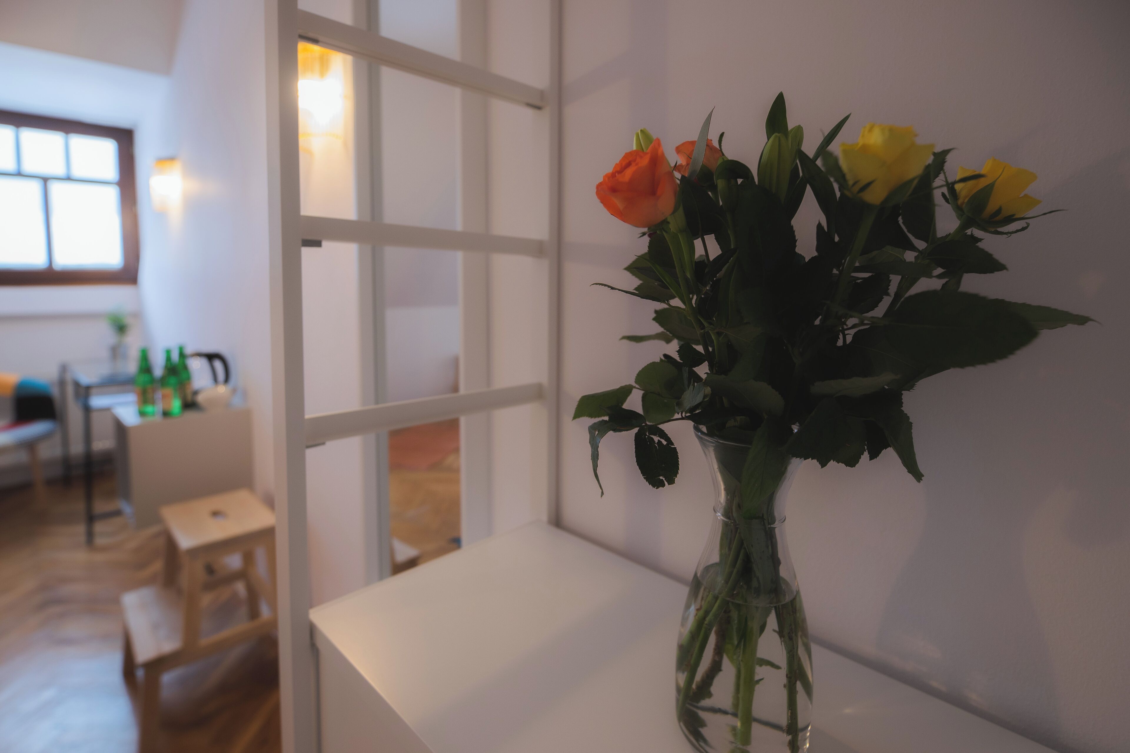 Una habitación con una mesa blanca y un florero en el alféizar de una ventana.