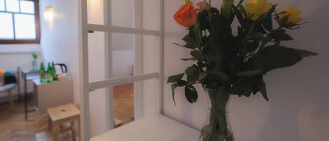 Una habitación con una mesa blanca y un florero en el alféizar de una ventana.