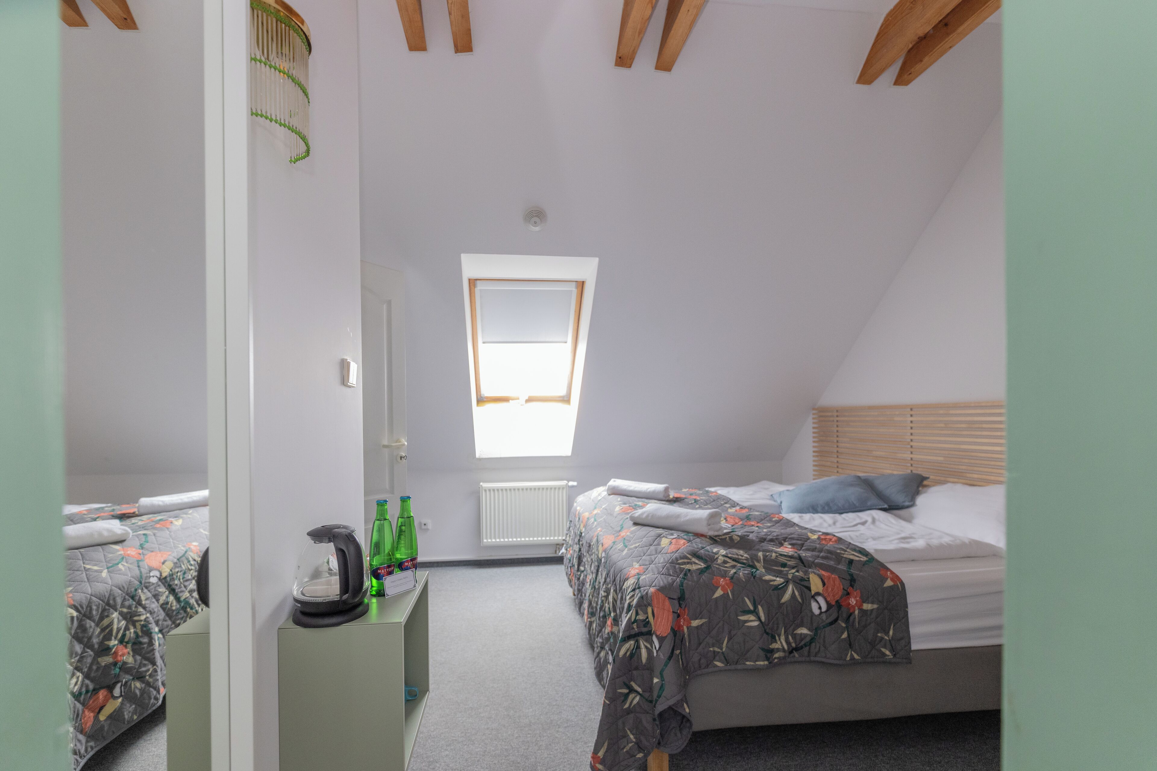 Une chambre avec deux lits, une fenêtre et un radiateur.