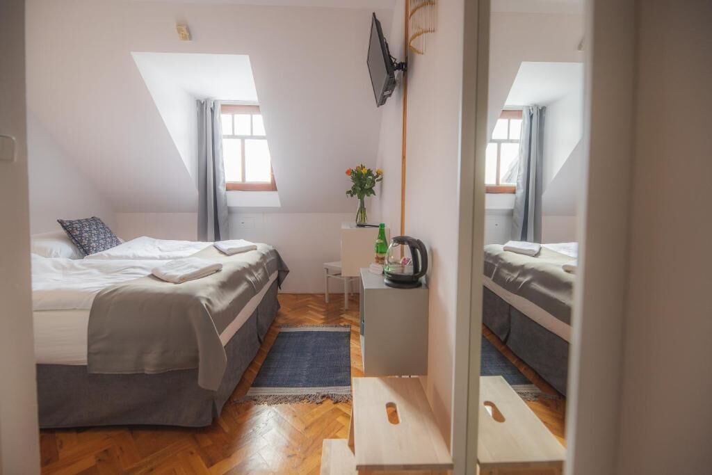 Een kleine, goed verlichte kamer met twee bedden, een klein tafeltje met een waterkoker en een spiegel.